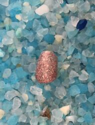 A sparkle nail, discarded after a week of art openings, in a sea of cat litter